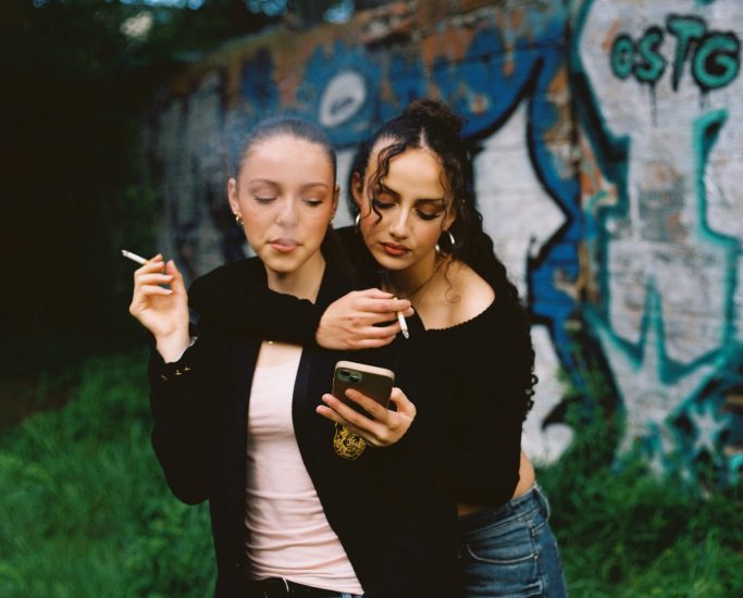 Deux femmes en train de fumer regarde un téléphone portable. Copyright d'Armony Dailly